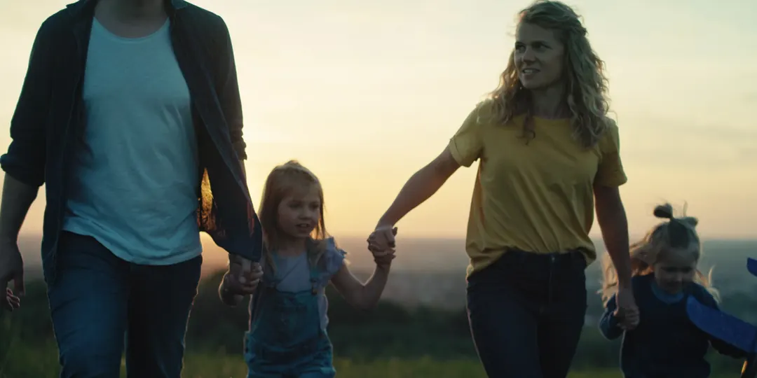 A family walking hand in hand across a field at sunset