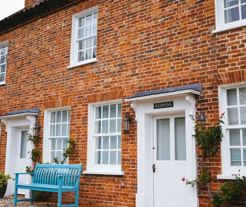 A red-brick terraced house with a blue bench by the front door