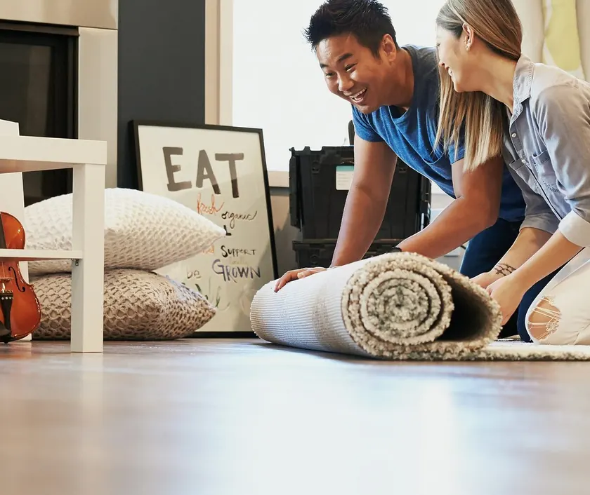 A couple unrolling a rug in their living room