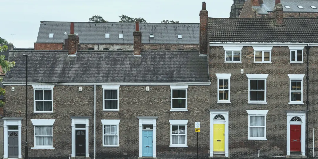 A row of brick terraced houses with brightly painted front doors