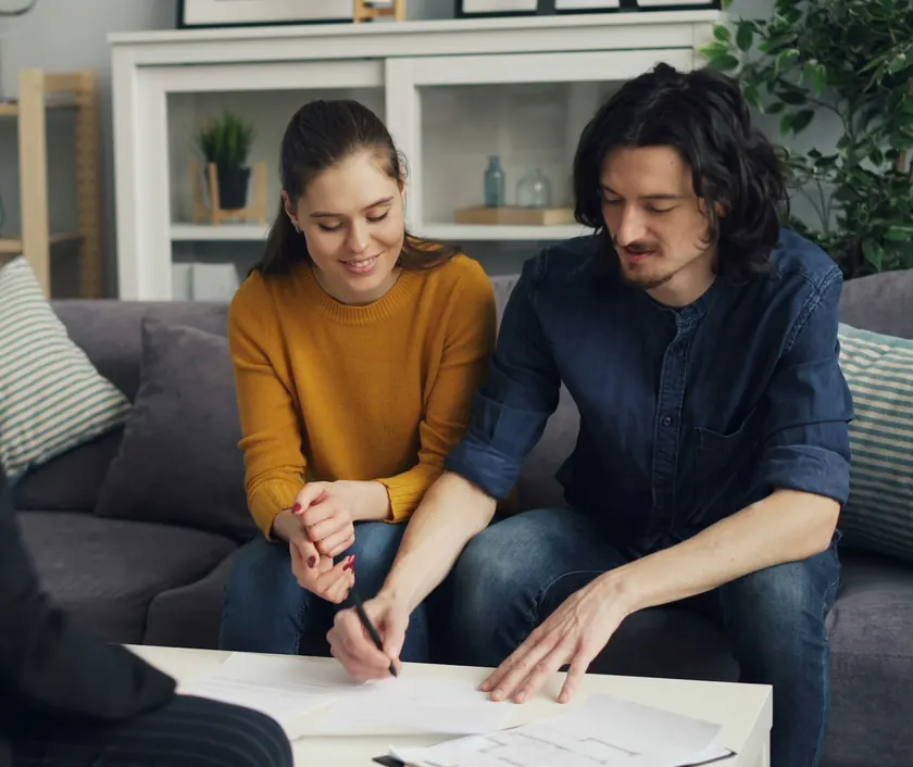 An adviser going through paperwork with a young couple in their living room