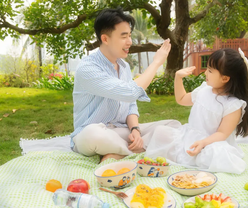 A father and daughter sharing a high five at a picnic